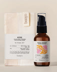 Banyo brand products including a Kese glove and Petal Woods body oil on a beige background
