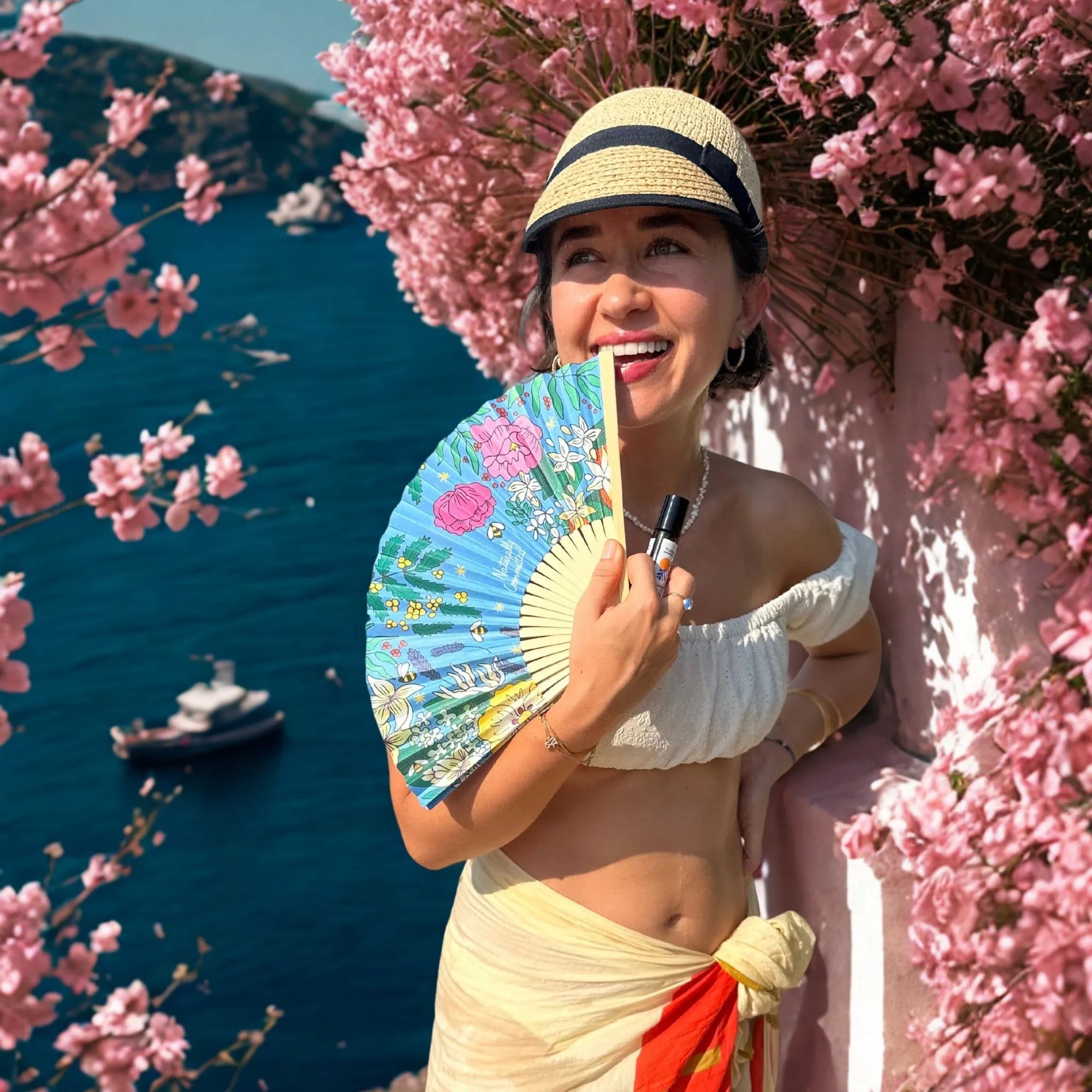 Woman holding a colorful fan by a cherry blossom tree with a scenic background