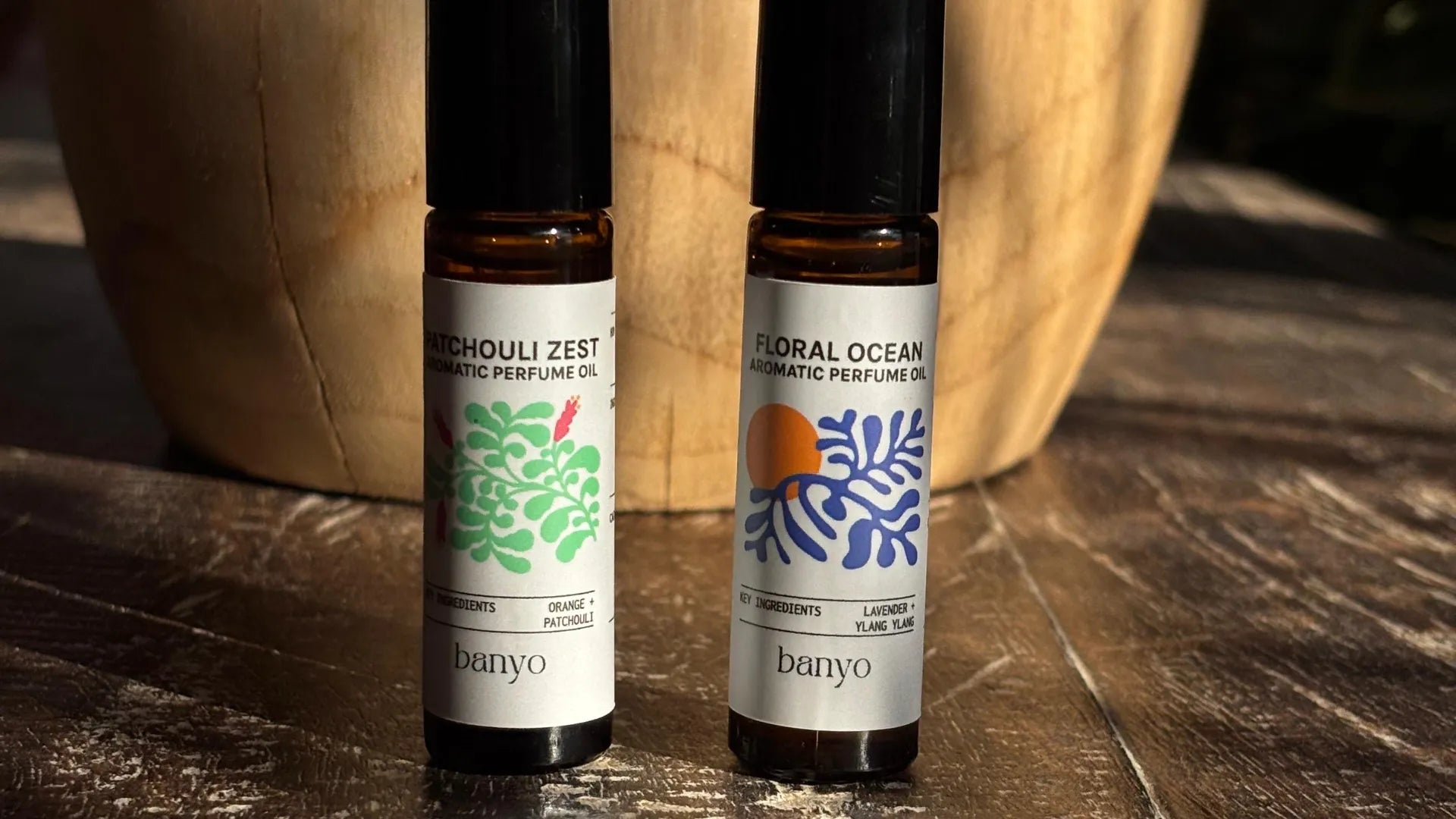 Two bottles of banyo organic perfume oils on a wooden surface