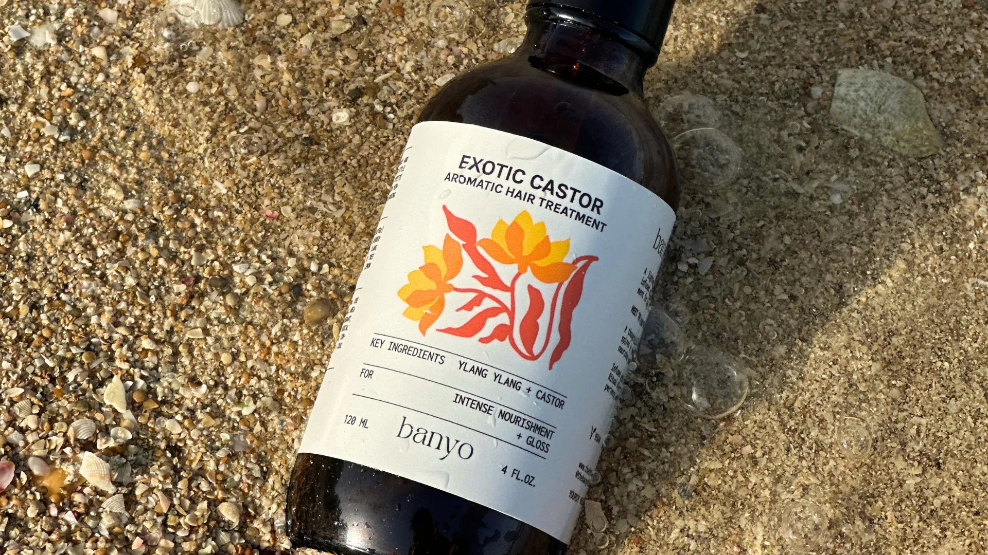 Bottle of Exotic Castor hair treatment on a sandy surface